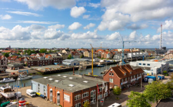 Eine erhöhte Ansicht auf Hafenbecken, Lagerhallen und Backsteingebäude unter einem leicht bewölkten Himmel.