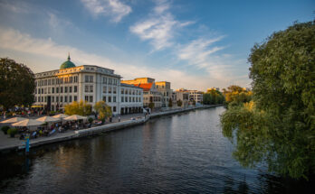 Klassische helle Gebäude und Cafés mit Sonnenschirmen säumen das ruhige Ufer der Havel unter einem weiten Abendhimmel.