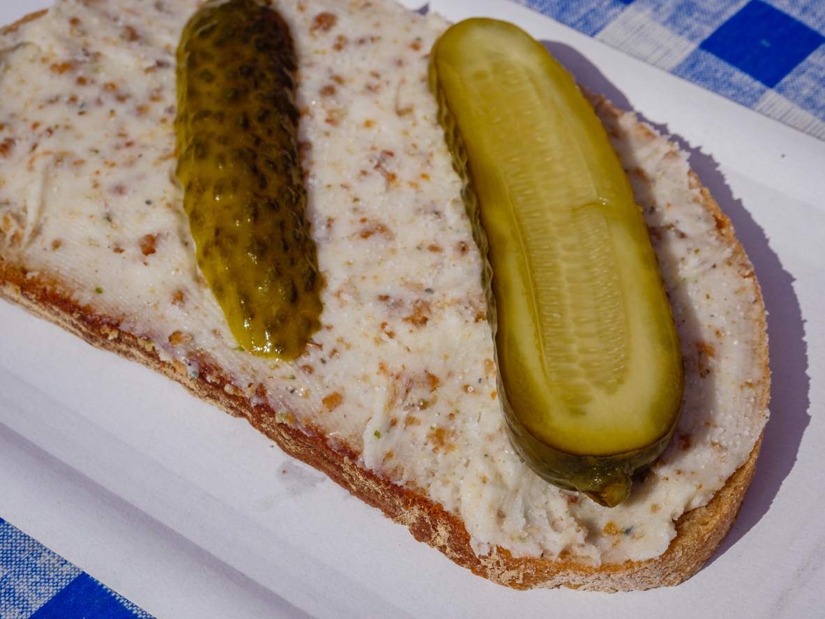 Brot mit Schmalz und zwei Spreewaldgurken auf kariertem Tuch.