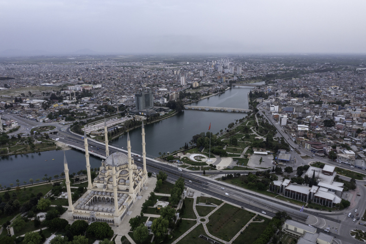 Eine Luftaufnahme zeigt die Sabancı-Zentralmoschee im Vordergrund und die historische Steinbrücke Taşköprü, die den Seyhan-Fluss überquert.