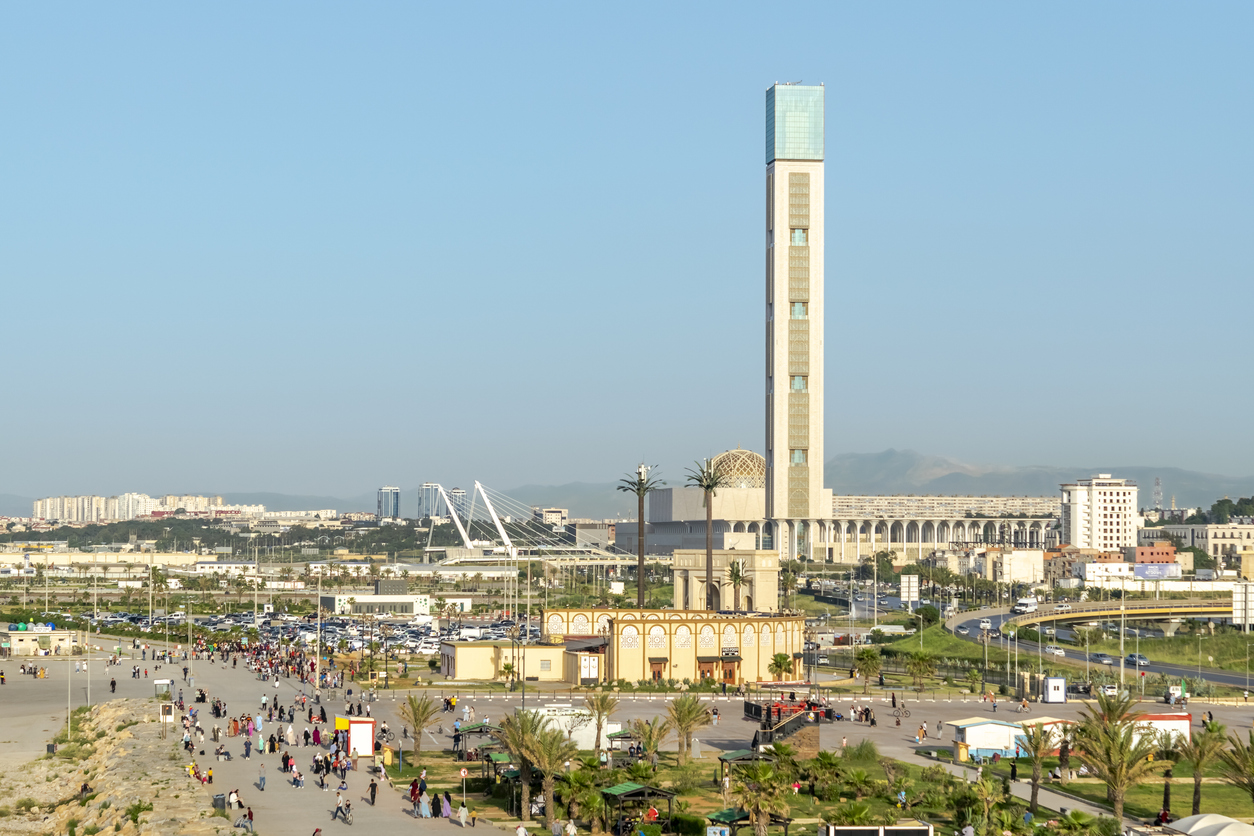 Blick auf die Große Moschee von Algier mit hohem Minarett und Vorplatz am Stadtrand.