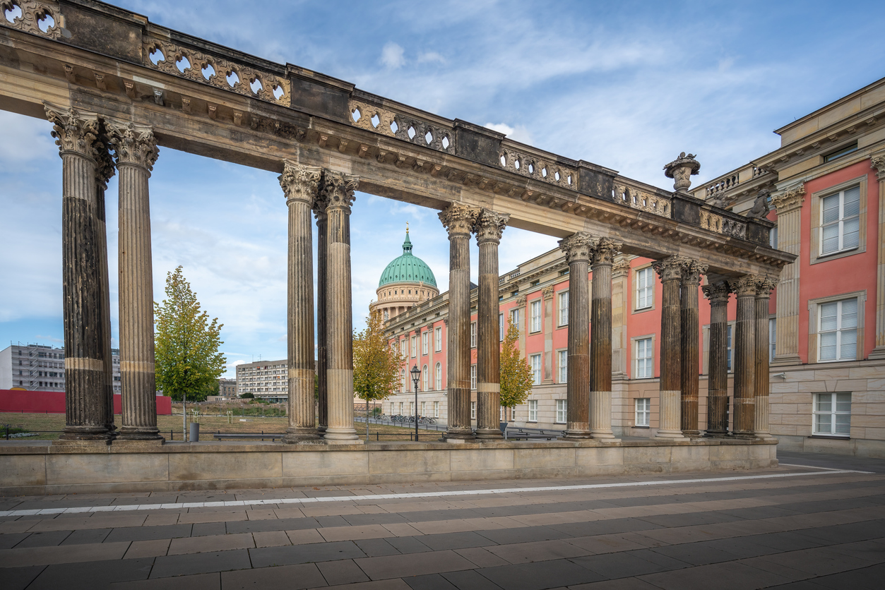Eine Reihe antiker Säulen mit verzierten Kapitellen rahmt den Blick auf die große grüne Kuppel der St. Nikolaikirche ein.