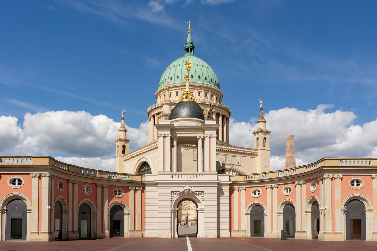 Das monumentale klassizistische Kirchengebäude mit seiner großen grünen Kuppel steht hinter einem hohen Obelisken auf einem weiten, gepflasterten Platz.
