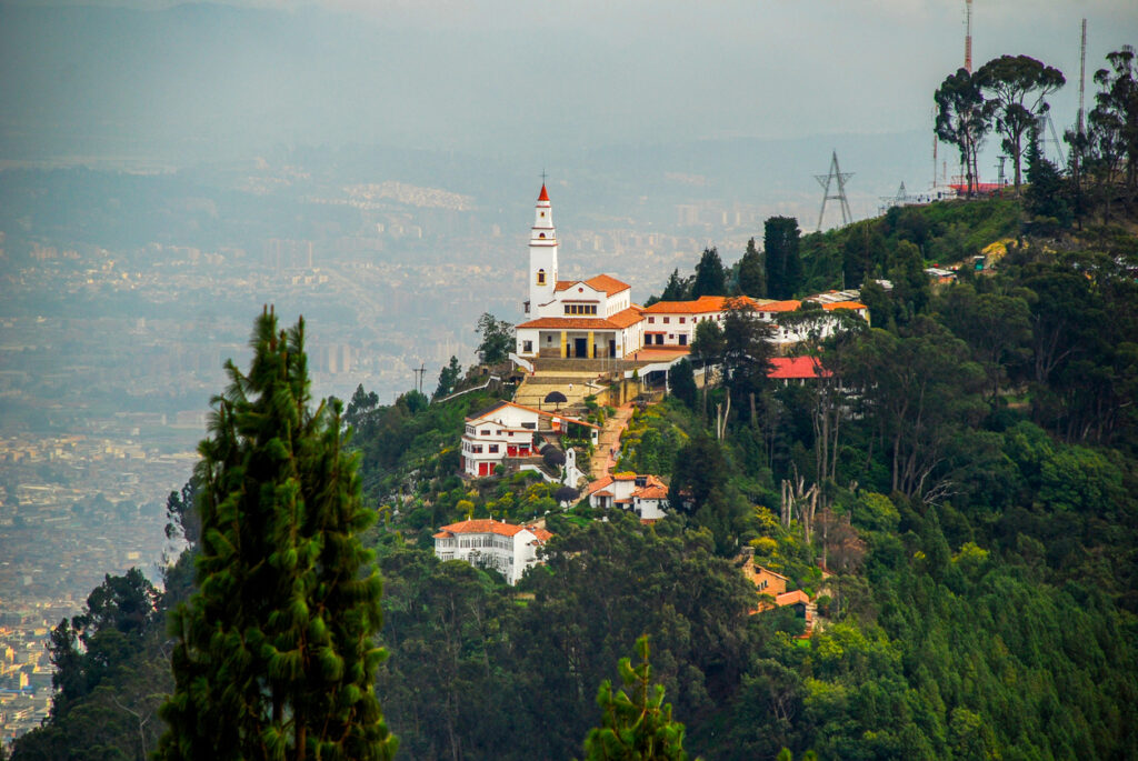 Die weiße Kirche Monserrate thront auf einem bewaldeten Berggipfel hoch über der dunstigen Stadt Bogotá.