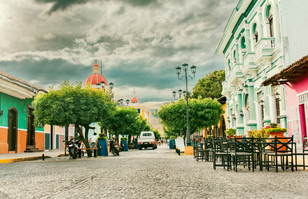 Bunte Straße mit Kolonialhäusern und Kirchenkuppel in Granada in Nicaragua.