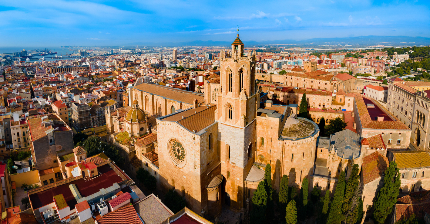 Eine Drohnenansicht der massiven Kathedrale mit ihrer großen Rosette und dem markanten Glockenturm inmitten der dichten Altstadtbebauung.