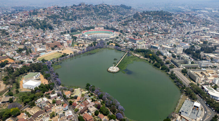 Eine Luftaufnahme zeigt den Lac Anosy im Vordergrund, dahinter erstrecken sich die dicht bebauten Hügel der Stadt bis zum Horizont.