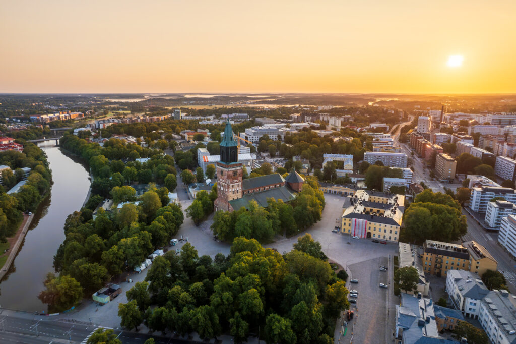 Luftaufnahme von Turku während eines Sonnenuntergangs mit Blick auf die Kathedrale, den Aura-Fluss und die umliegende Stadtlandschaft.