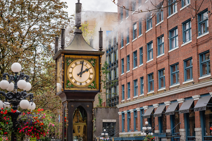 Die berühmte dampfbetriebene Standuhr „Steam Clock“ steht vor einem Backsteingebäude in Gastown, weißer Dampf steigt empor.
