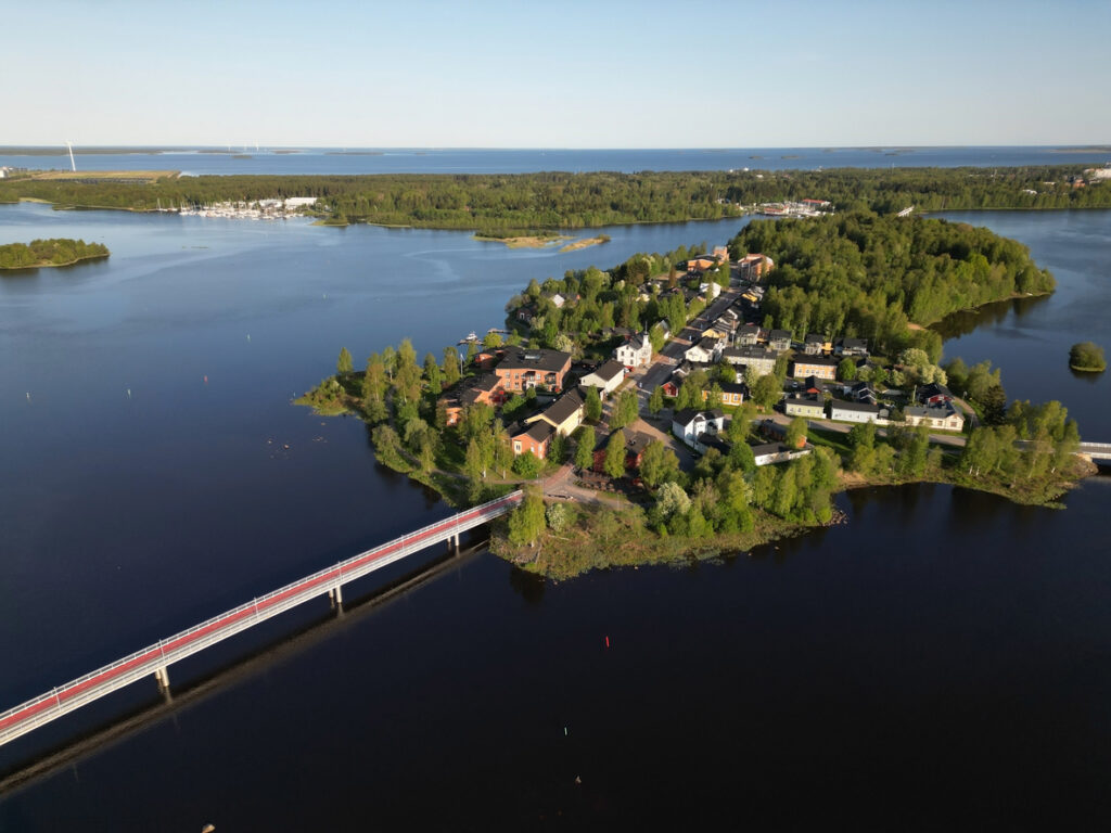 Luftaufnahme von Oulu mit einer Brücke, einer kleinen Insel mit Häusern und dunklem Wasser rundherum.