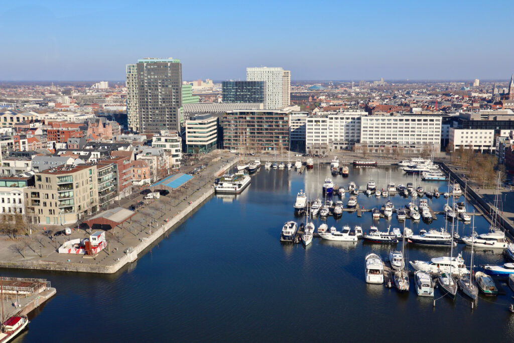 Blick auf ein Hafenbecken mit Yachten und moderner Skyline in Antwerpen.