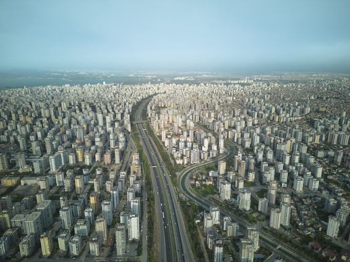 Eine Luftaufnahme zeigt das endlose Häusermeer von Adana, das von einer breiten Autobahn und einem Grünstreifen durchschnitten wird.