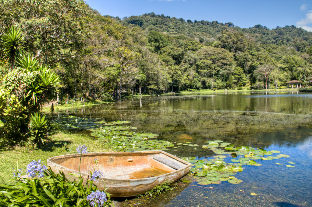 Kleines Boot liegt an einem See mit Seerosen und grünen Hügeln in Nicaragua.