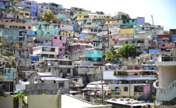 Ein dichtes Häusermeer aus grauen Betonbauten und bunt gestrichenen Fassaden erstreckt sich über einen steilen Hang.