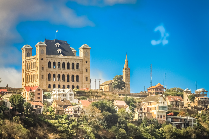 Der historische Königspalast aus gelbem Stein mit markanten Ecktürmen thront auf einem Hügel über farbenfrohen Wohnhäusern.