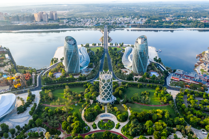 Eine Luftaufnahme zeigt modernste Hochhäuser in geschwungener Form direkt an einer Bucht, umgeben von weitläufigen Parkanlagen.