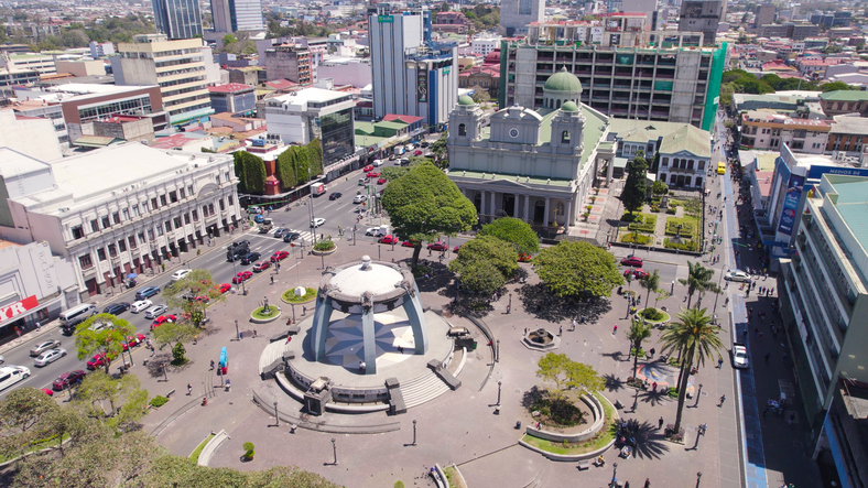 Eine Luftaufnahme eines weiten Stadtplatzes mit einem kreisrunden Pavillon in der Mitte, im Hintergrund die Metropolitan-Kathedrale und Stadtgebäude.